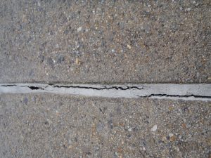 A crack has formed in the concrete joint sealant.