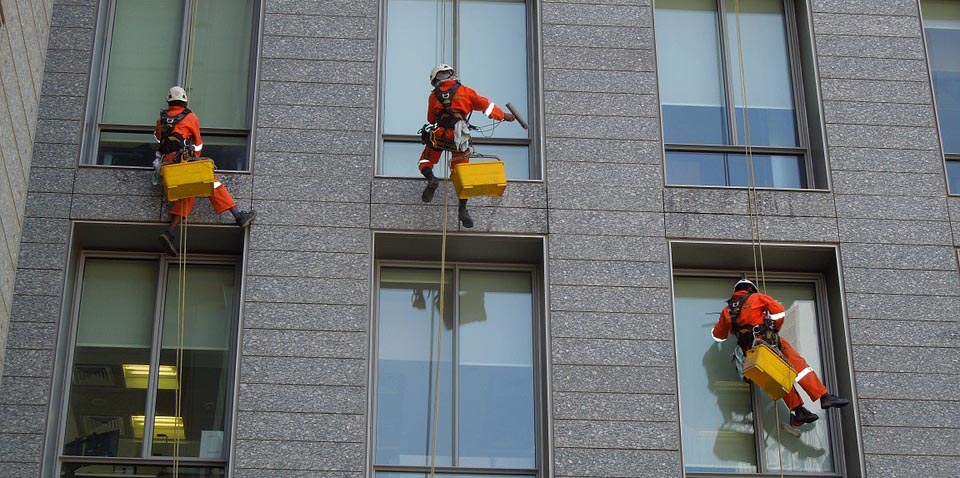 Workers cleaning windows while suspended